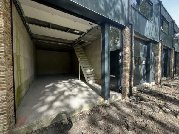 Open garagebox aan Broekdijk-West 19-4 met een betonnen vloer en een trap naar boven.